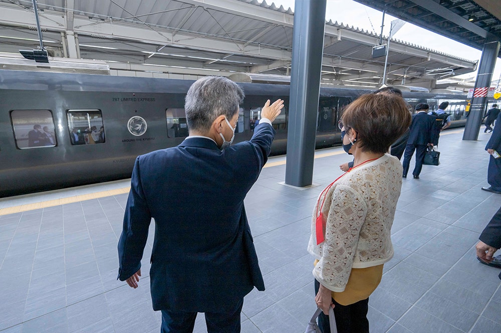 武雄温泉駅で稲田鉄道調査会長に、対面乗り換え方式について説明する古宮社長。「ホームの幅は約10m、開業前に乗り換えの模擬実験を行い、時間は約3分に設定しました」と古宮社長